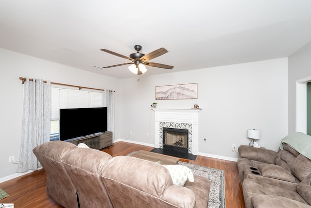 living room with wood finished floors, a ceiling fan, baseboards, and a tile fireplace