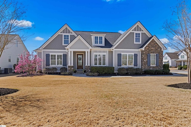 view of front of home featuring a front yard, cooling unit, and stone siding