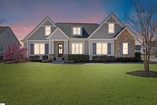 craftsman-style house featuring stone siding and a front yard