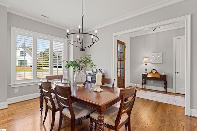 dining room featuring visible vents, a notable chandelier, light wood-style flooring, crown molding, and baseboards