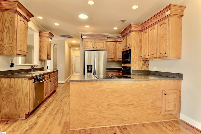 kitchen featuring dark countertops, visible vents, a peninsula, black appliances, and a sink