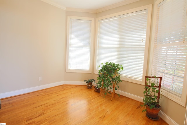 empty room featuring crown molding, baseboards, and wood finished floors