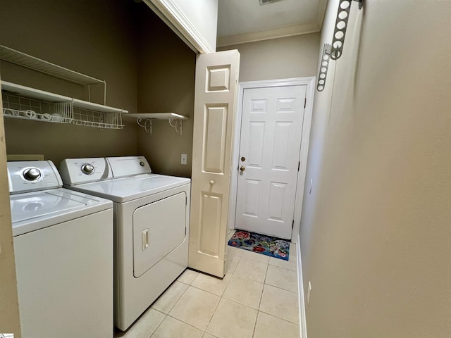 clothes washing area with light tile patterned floors, separate washer and dryer, ornamental molding, and laundry area