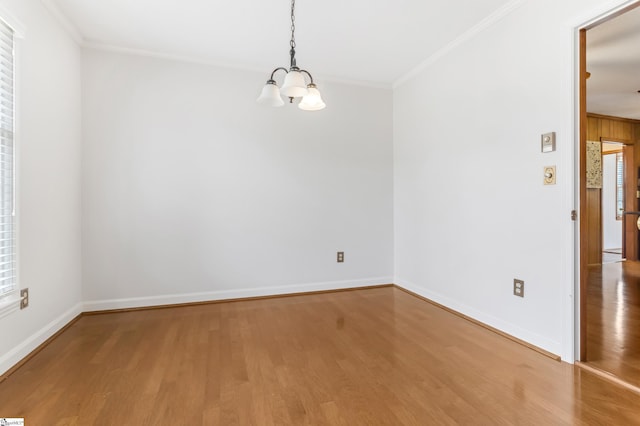 unfurnished room featuring a notable chandelier, crown molding, and wood finished floors