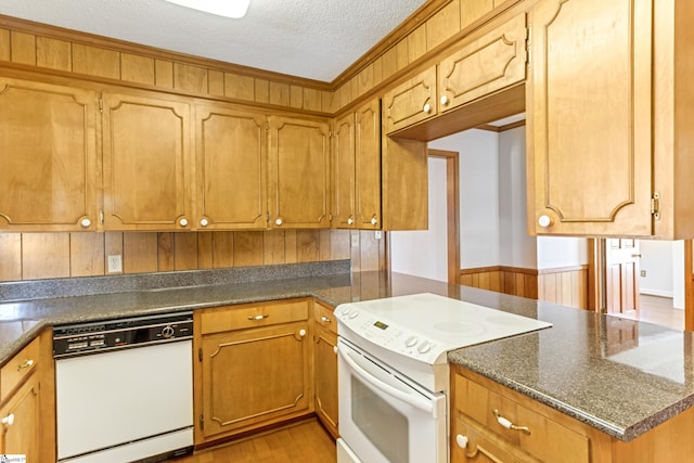 kitchen featuring white appliances, light wood finished floors, a textured ceiling, dark countertops, and brown cabinets