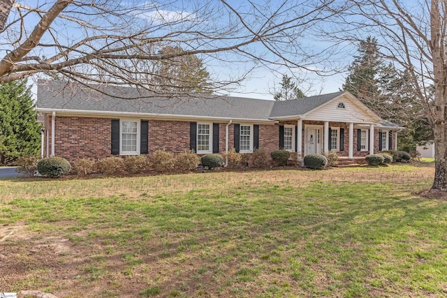 view of front of home featuring a front lawn, a porch, brick siding, and a shingled roof