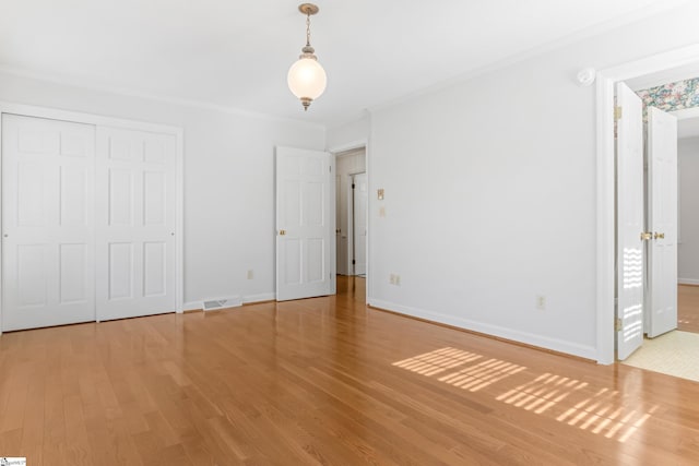 unfurnished bedroom featuring visible vents, baseboards, and wood finished floors