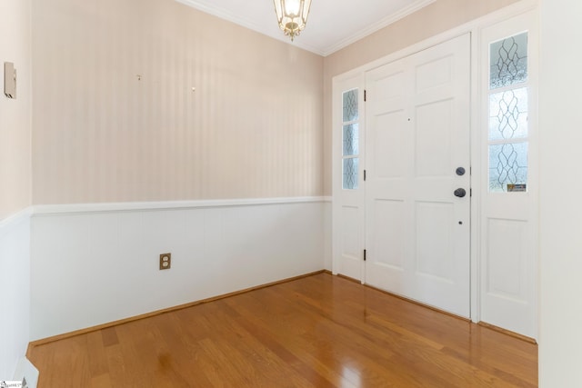 entryway featuring crown molding, wood finished floors, and a wainscoted wall