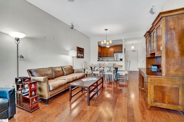 living room with ceiling fan with notable chandelier and hardwood / wood-style flooring