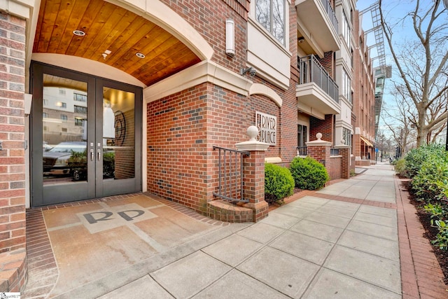 view of exterior entry featuring french doors and brick siding