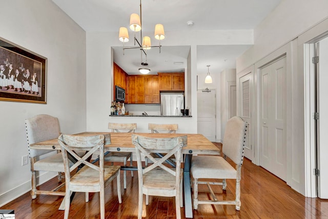 dining space featuring an inviting chandelier, baseboards, and wood finished floors