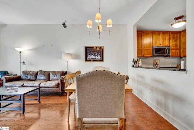 living area featuring baseboards, an inviting chandelier, and wood finished floors