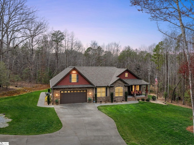 view of front of house featuring a lawn, driveway, covered porch, a shingled roof, and a garage