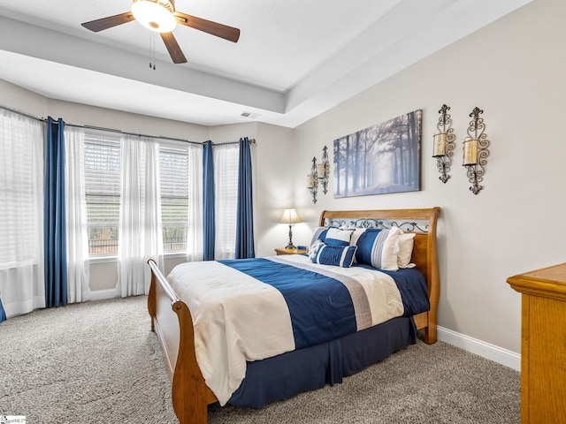 bedroom with a ceiling fan, visible vents, carpet, baseboards, and a tray ceiling