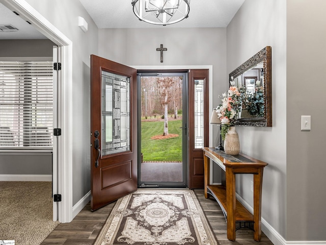 foyer entrance with wood finished floors, baseboards, and visible vents