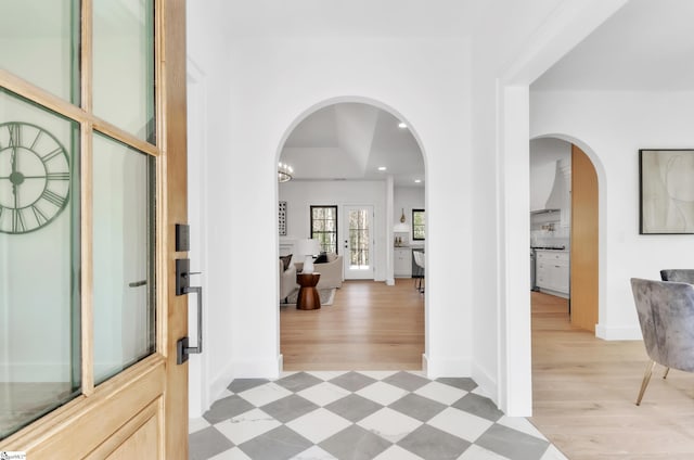 entryway featuring recessed lighting, light floors, arched walkways, and baseboards