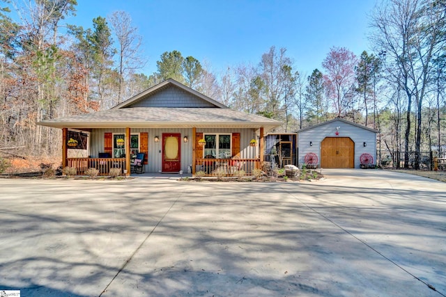 view of front facade featuring board and batten siding, covered porch, an outdoor structure, a garage, and driveway