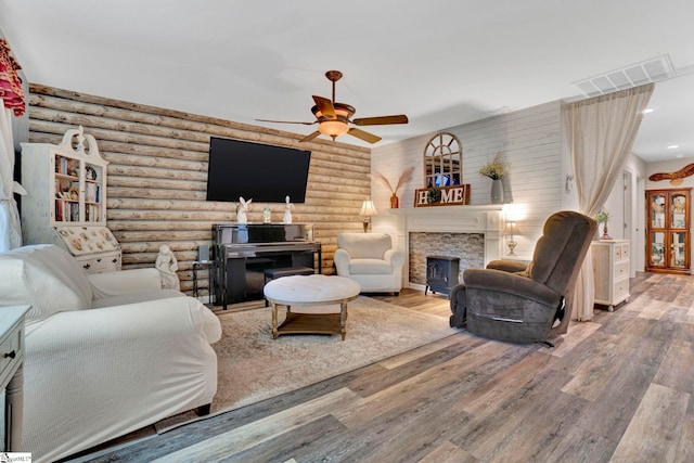 living room featuring rustic walls, visible vents, wood finished floors, and a fireplace