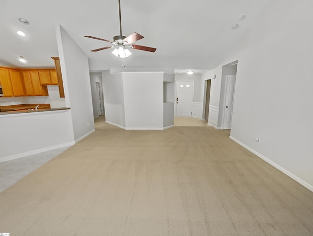 unfurnished living room with light carpet, baseboards, and ceiling fan