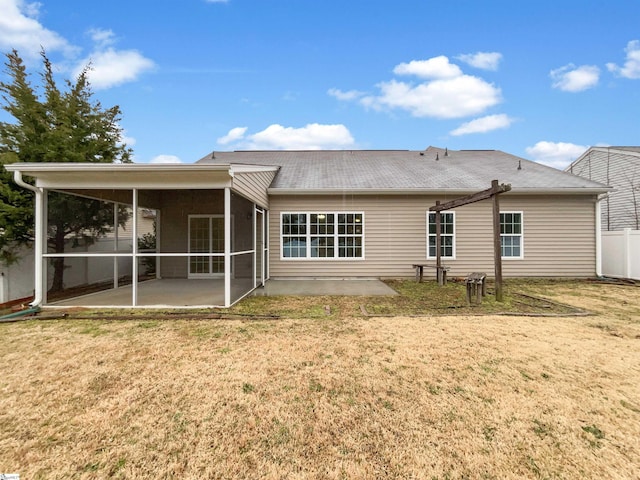 rear view of property featuring a yard, a sunroom, and a patio area