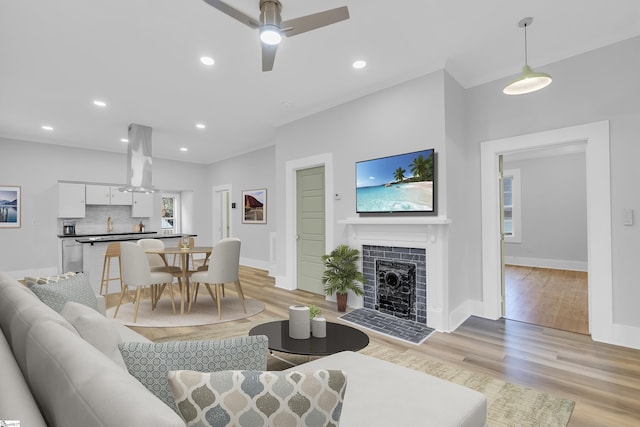 living room featuring ornamental molding, recessed lighting, light wood finished floors, ceiling fan, and a tile fireplace