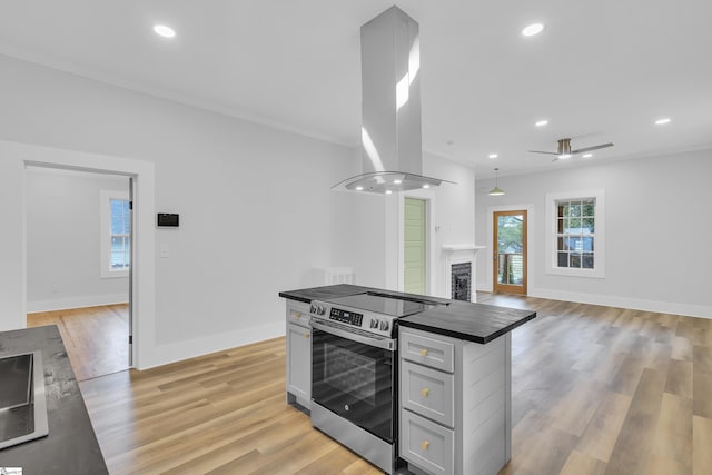 kitchen with stainless steel electric stove, recessed lighting, island exhaust hood, light wood-style floors, and dark countertops