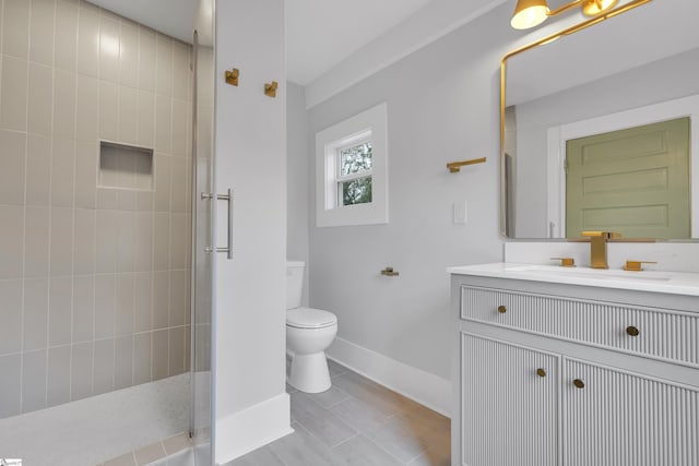 bathroom featuring baseboards, tiled shower, toilet, and vanity