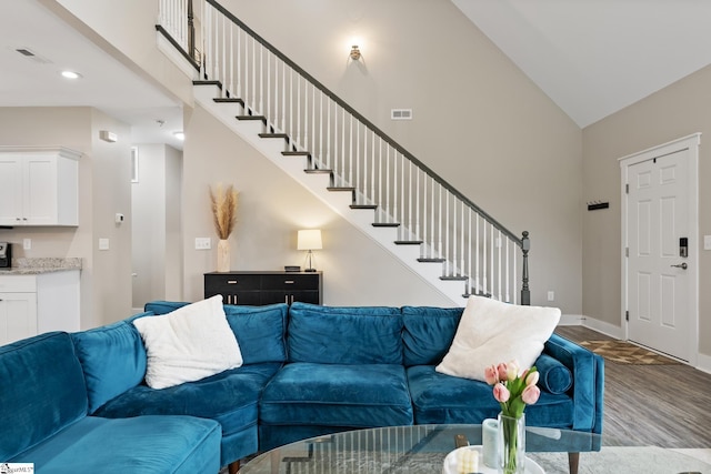 living room featuring visible vents, high vaulted ceiling, wood finished floors, and stairs