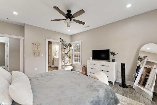 bedroom featuring wood finished floors, visible vents, baseboards, recessed lighting, and connected bathroom