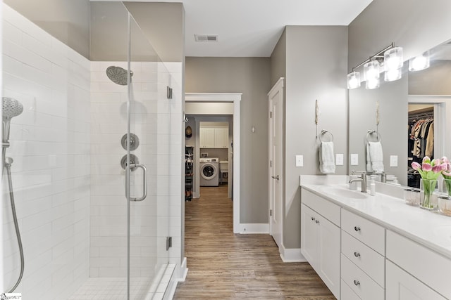 bathroom with visible vents, a stall shower, washer / clothes dryer, and wood finished floors