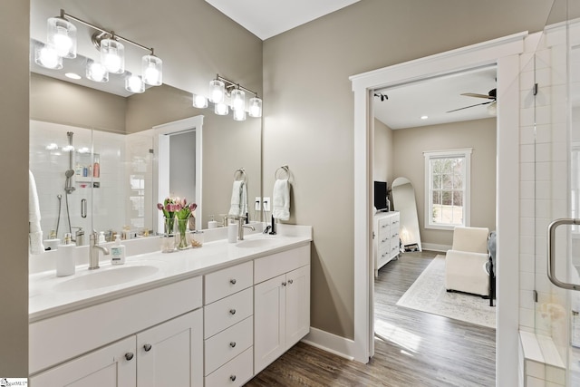 ensuite bathroom featuring wood finished floors, ensuite bath, ceiling fan, a sink, and a shower stall