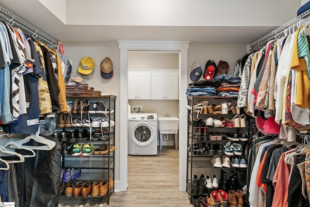 walk in closet with washer / dryer, wood finished floors, and a sink