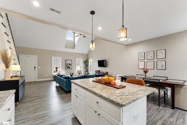 kitchen with visible vents, a center island, open floor plan, wood finished floors, and white cabinetry