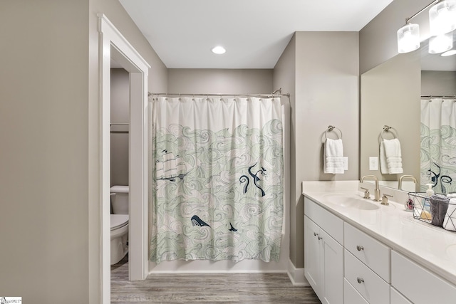 bathroom with toilet, wood finished floors, and vanity