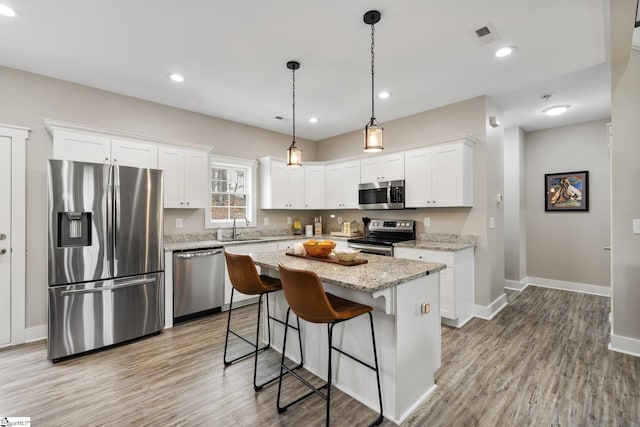 kitchen featuring a sink, a kitchen breakfast bar, appliances with stainless steel finishes, and white cabinets