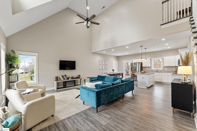 living room with a ceiling fan, recessed lighting, wood finished floors, and high vaulted ceiling