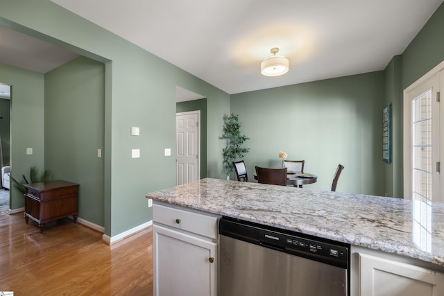 kitchen with light stone countertops, baseboards, white cabinetry, light wood-style floors, and dishwasher