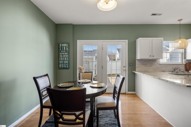 dining space with visible vents, baseboards, and light wood finished floors