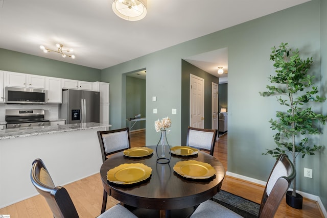 dining space featuring light wood-style flooring and baseboards