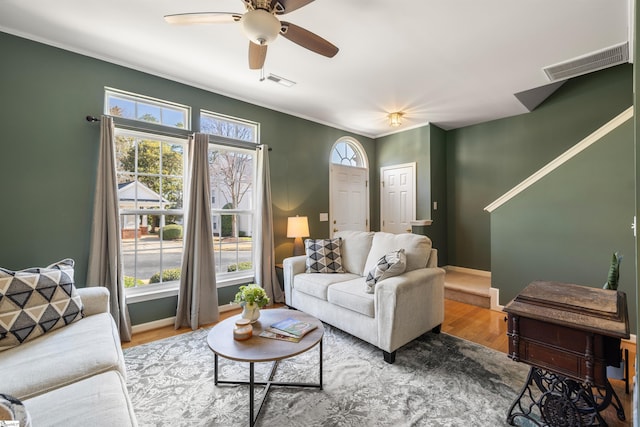 living area with ceiling fan, visible vents, baseboards, and wood finished floors