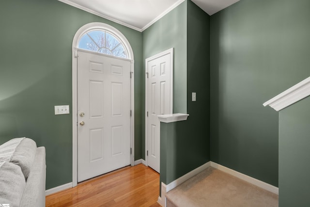 entryway featuring baseboards, crown molding, and light wood finished floors