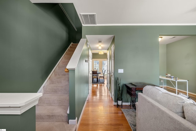 corridor featuring light wood-type flooring, visible vents, baseboards, and stairway