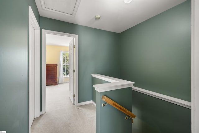 hall featuring baseboards, an upstairs landing, and light colored carpet