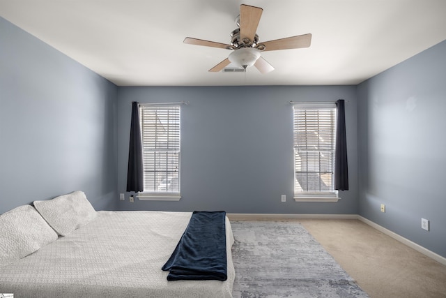 bedroom featuring carpet flooring, multiple windows, a ceiling fan, and baseboards