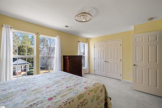 bedroom with visible vents, baseboards, a closet, and light carpet