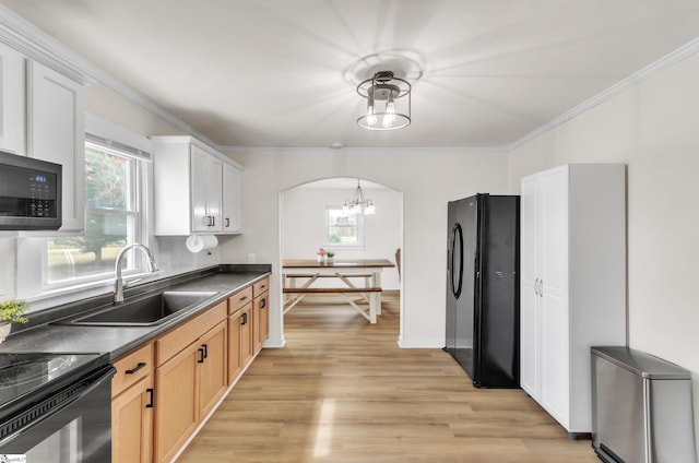 kitchen with dark countertops, ornamental molding, arched walkways, black appliances, and a sink