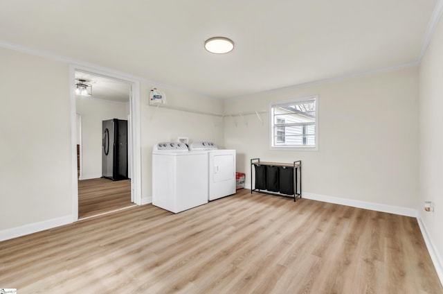 laundry room featuring baseboards, light wood finished floors, crown molding, and washer and clothes dryer