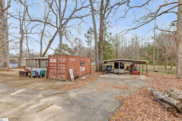 view of outdoor structure with an outbuilding, a carport, and driveway