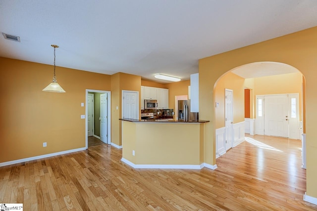 kitchen with stainless steel appliances, arched walkways, dark countertops, and visible vents