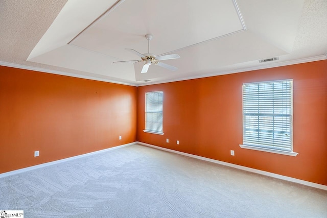 carpeted empty room with visible vents, ceiling fan, baseboards, and a tray ceiling